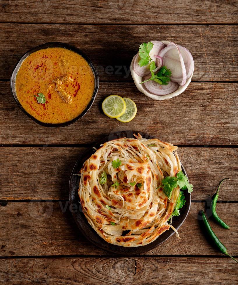 parotta - een Indisch brood gemaakt met meel welke is gekookt naar vlokkig knapperigheid en geserveerd met authentiek zuiden Indisch kip salna kurma foto