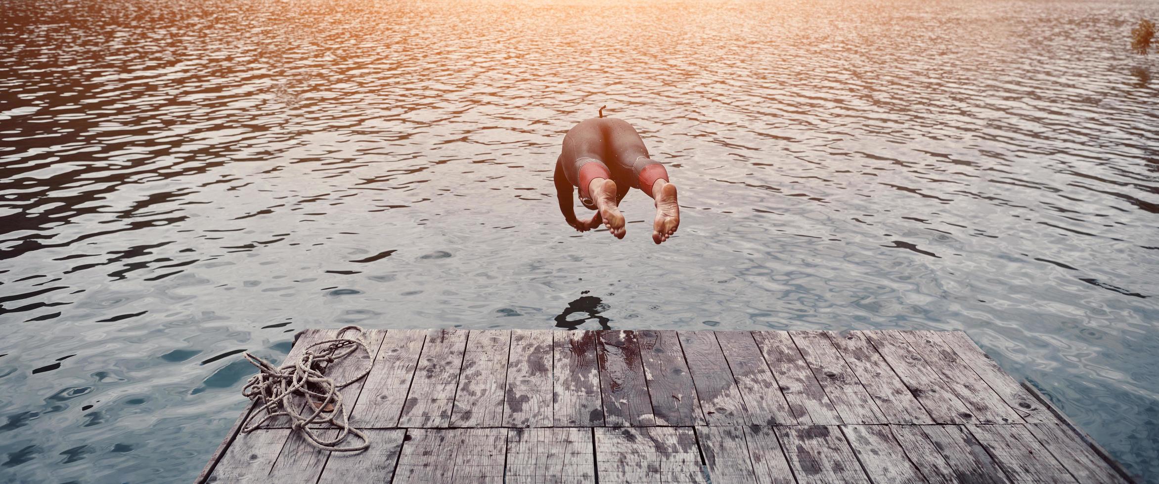 triatlon atleet jumping in water en beginnend met opleiding foto