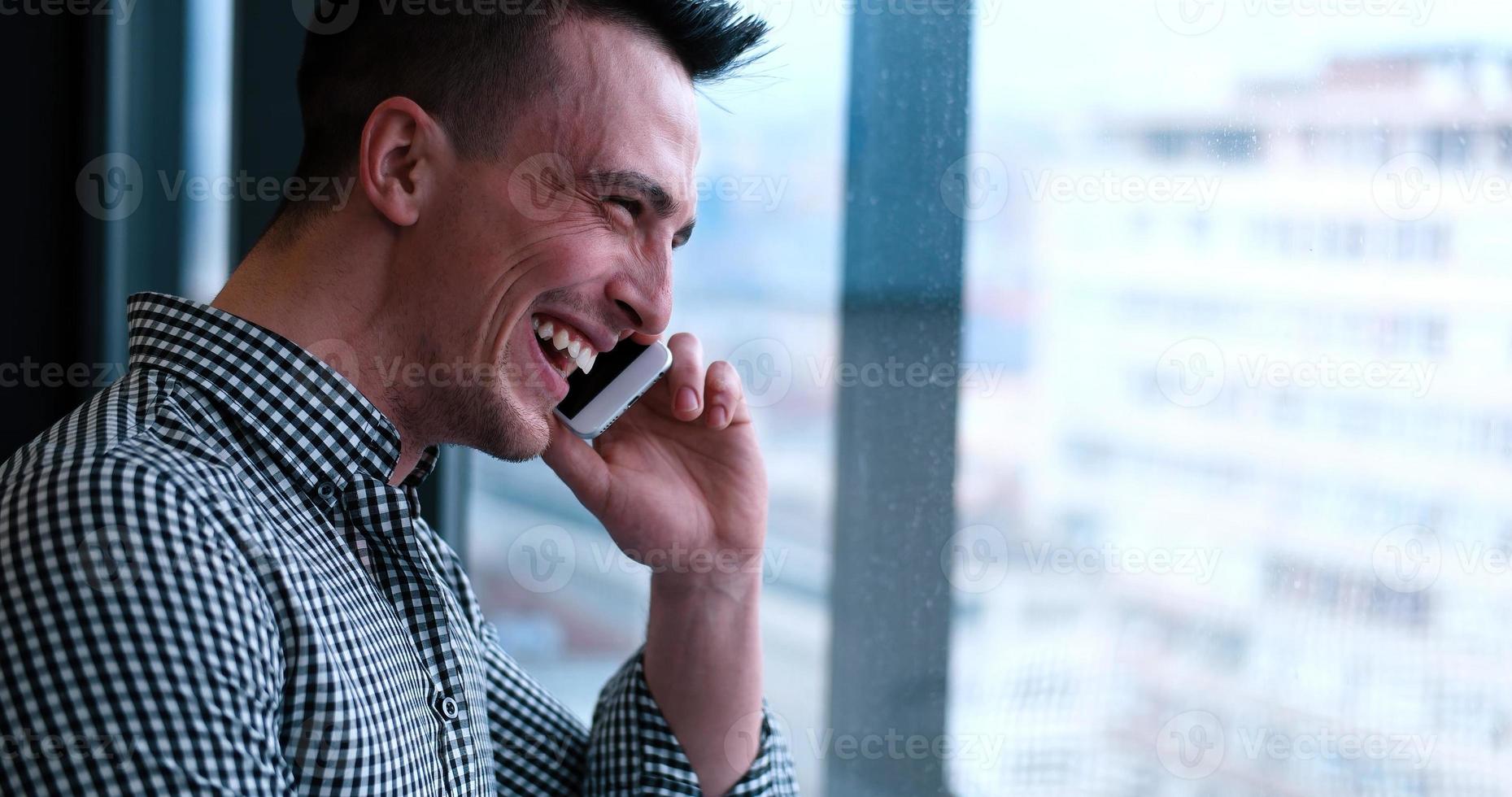 bedrijf Mens pratend Aan cel telefoon, op zoek uit kantoor venster foto