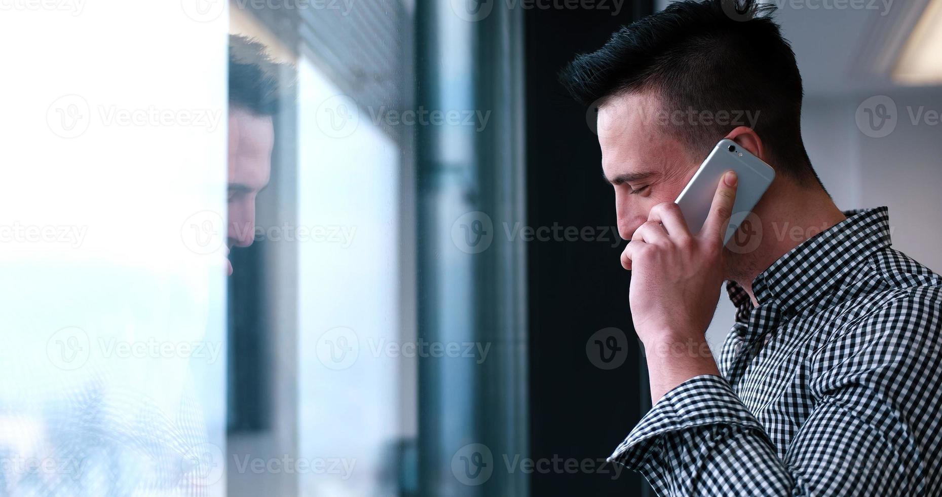 bedrijf Mens pratend Aan cel telefoon, op zoek uit kantoor venster foto