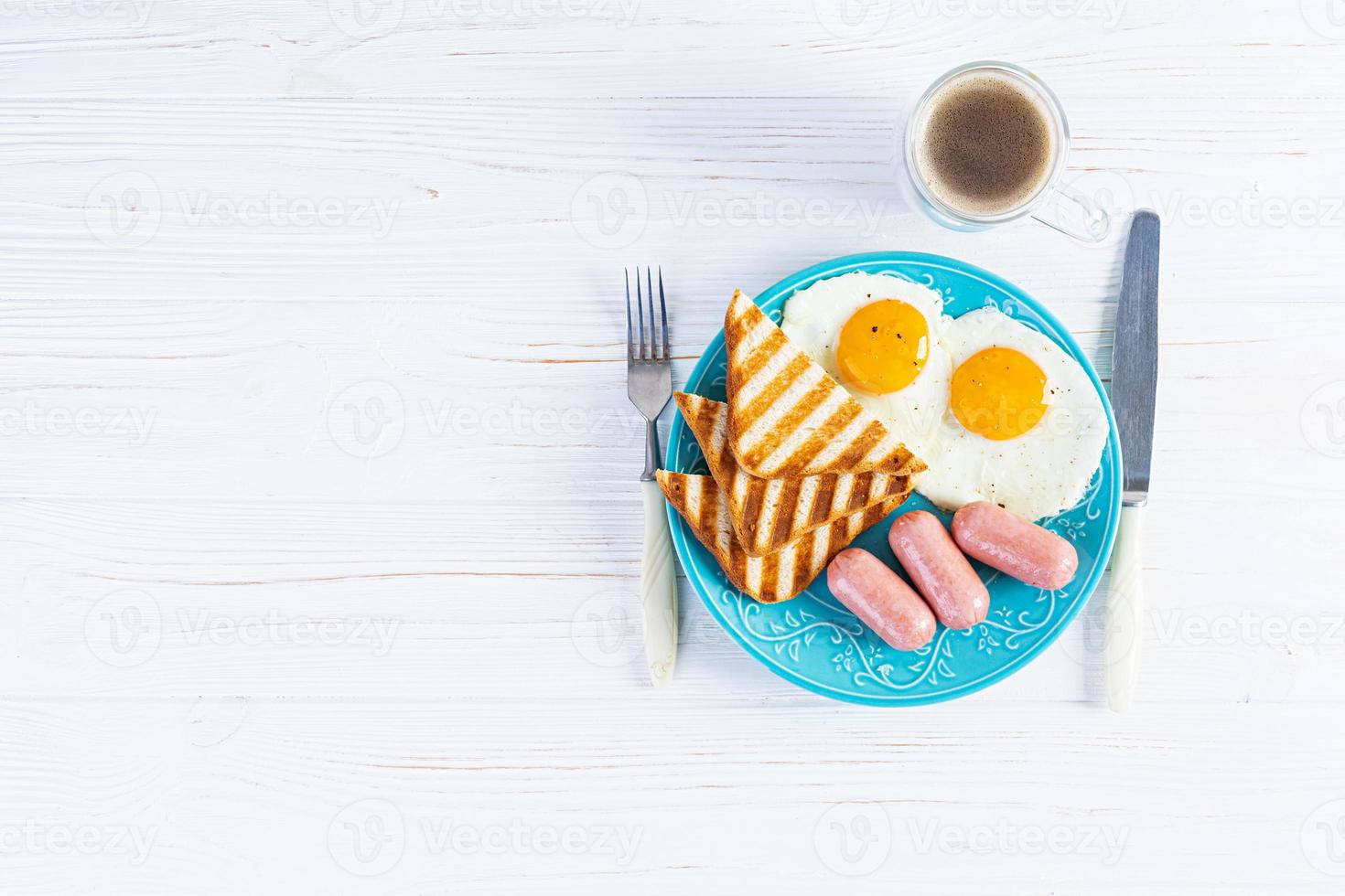 smakelijk ontbijt met eieren, worstjes, toast en kop van koffie. Amerikaans ontbijt. top visie foto