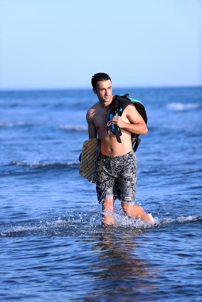 portret van een jong kitsurfen Mens Bij strand Aan zonsondergang foto