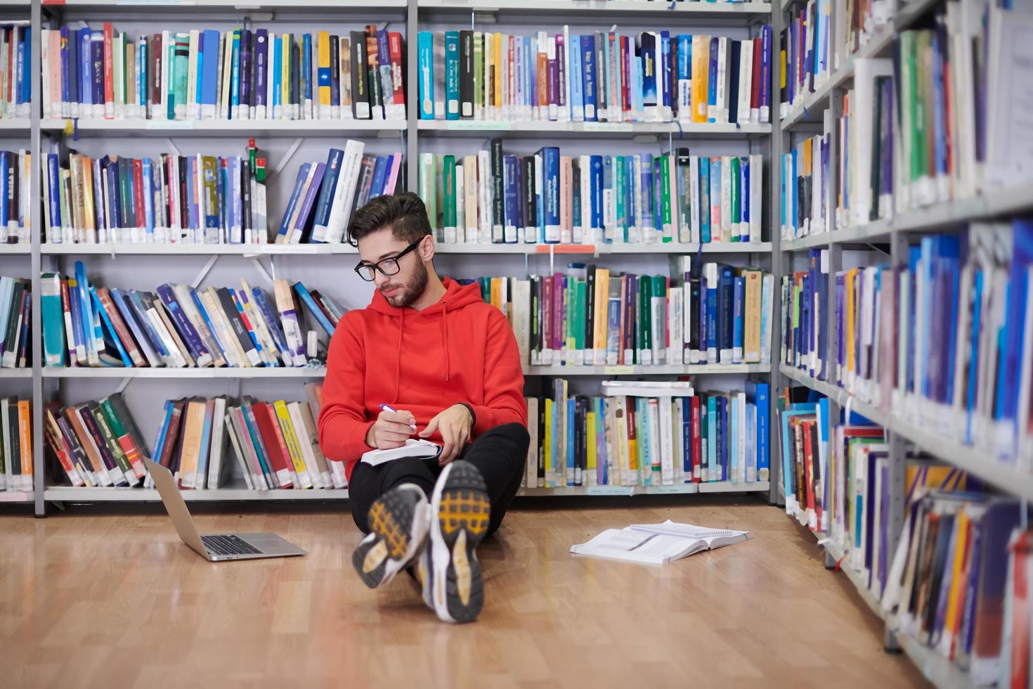 de studenten toepassingen een notitieboekje, laptop en een school- bibliotheek foto