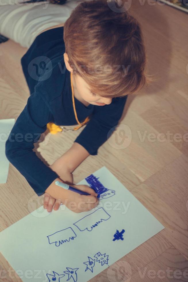 klein jongen tekening Aan de papier Bij huis. foto