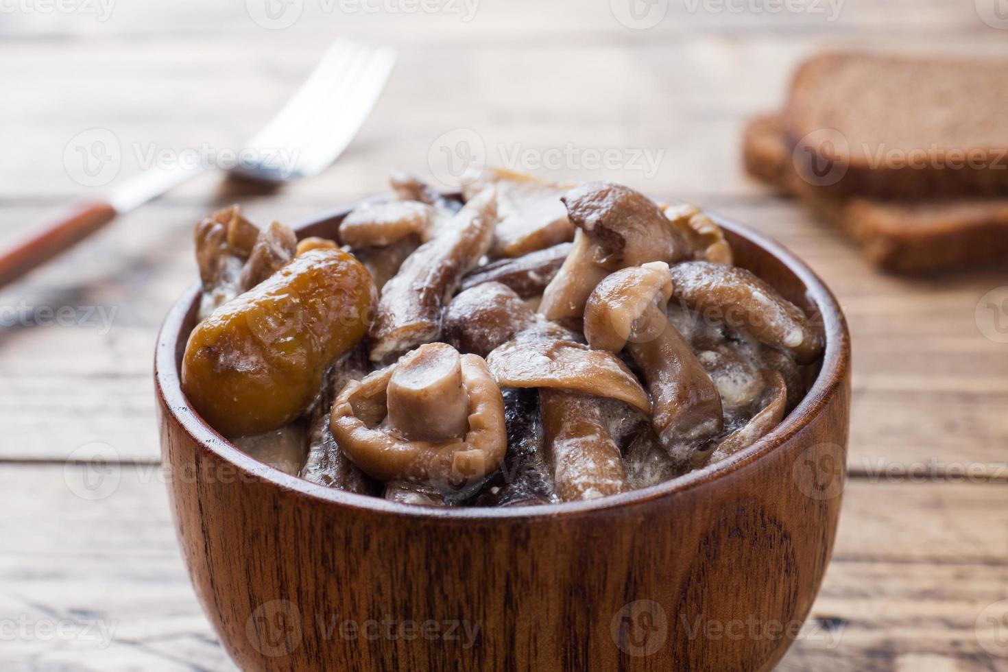 gestoofd champignons in een saus met verzuren room en kaas in een houten schaal. foto