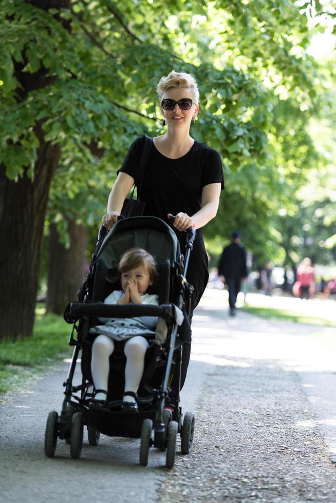 moeder geduwd haar baby dochter in een wandelwagen foto