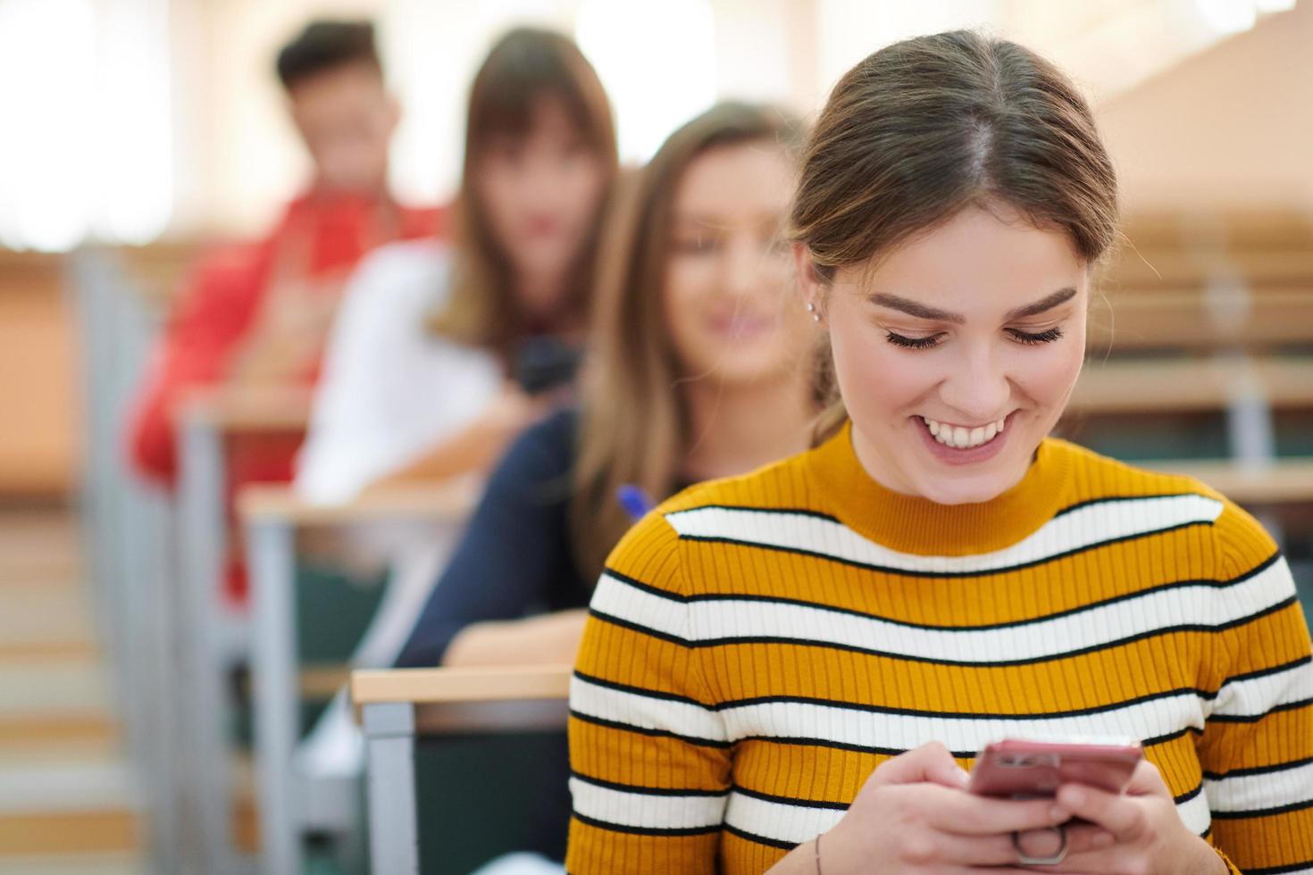 famel studenten gebruik makend van smartphone in klas foto