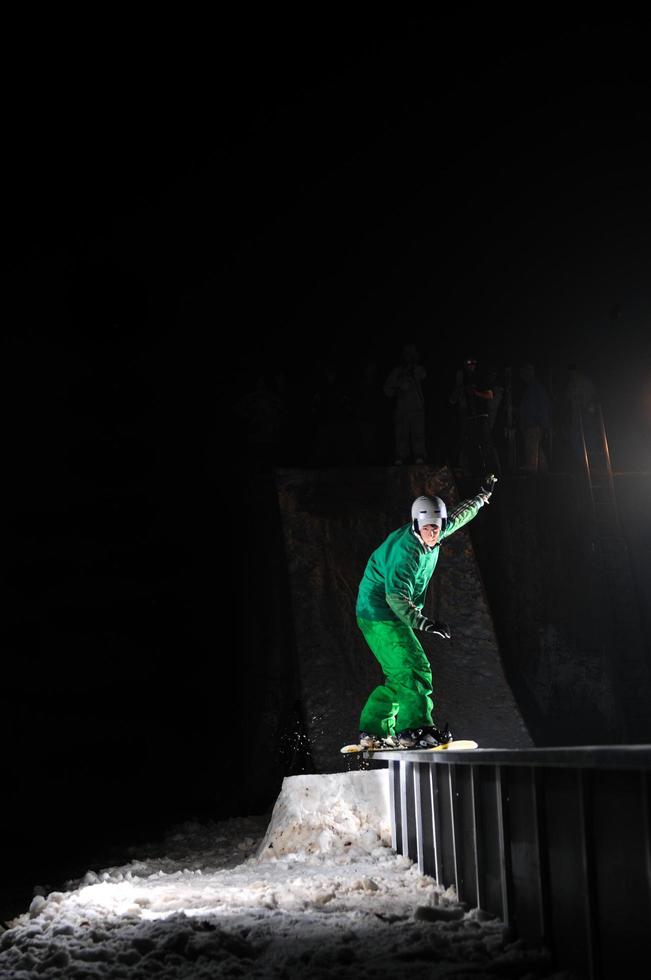 vrije stijl snowboarder springen in lucht Bij nacht foto