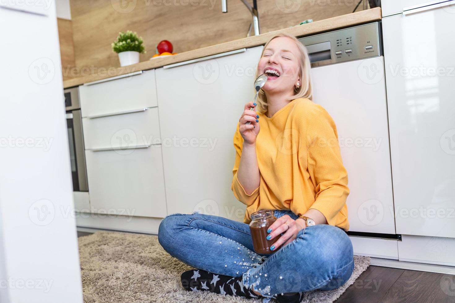 mooi jong albino meisje in gewoontjes kleren proeverij heerlijk chocola verspreiding terwijl zittend Aan de houten verdieping in de huiselijk keuken. foto