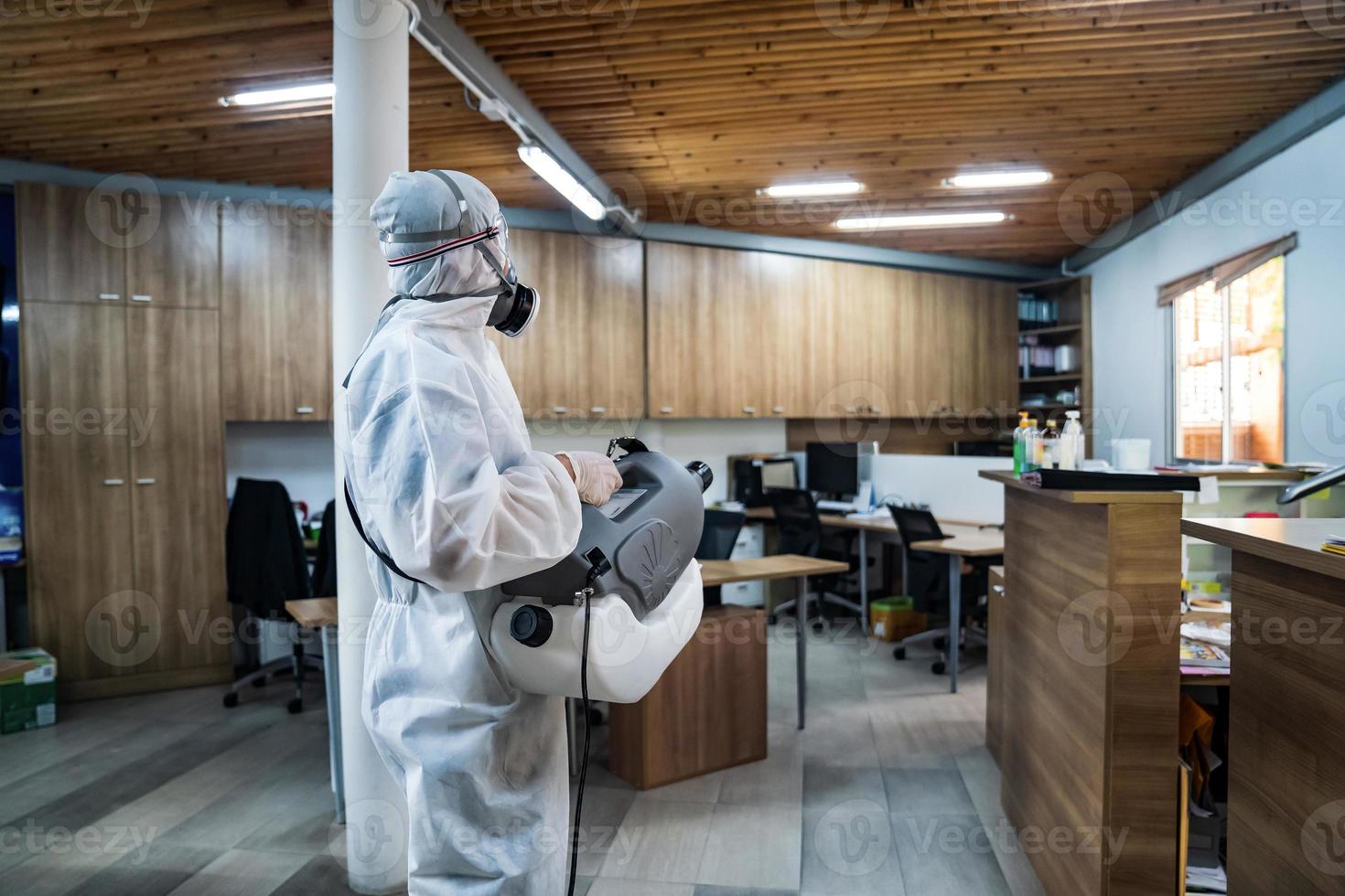 professioneel technisch Mens in het voorkomen pak met zijn steriliseren machine en desinfecteren water sprays allemaal gebieden in de kantoor kamer naar nemen zuiverend coronavirus covid19 foto