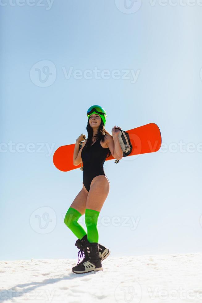 jonge mooie vrouw poseren met een snowboard op een skipiste foto