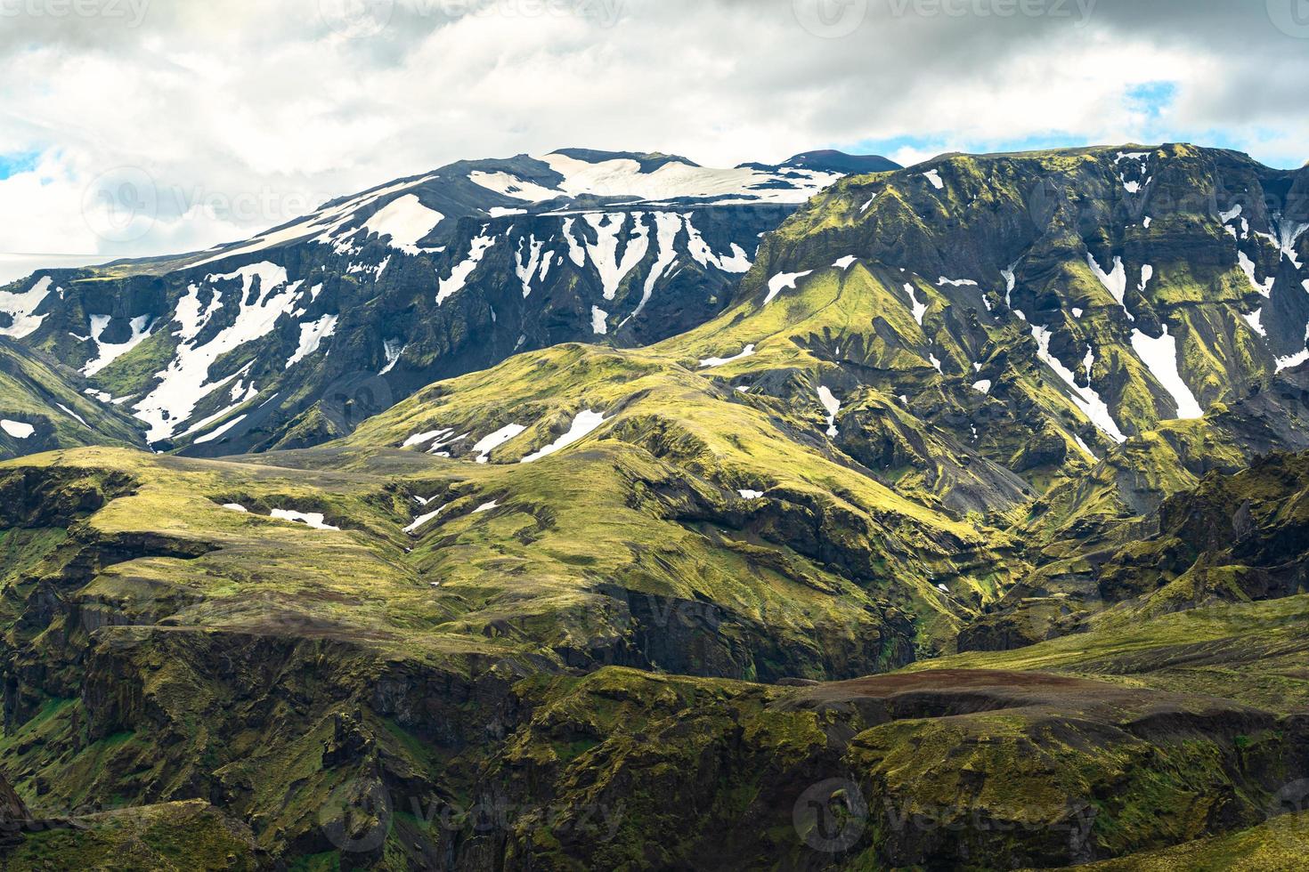 groen berg met mos ruw structuur en sneeuw gedekt in IJslands hooglanden Bij IJsland foto