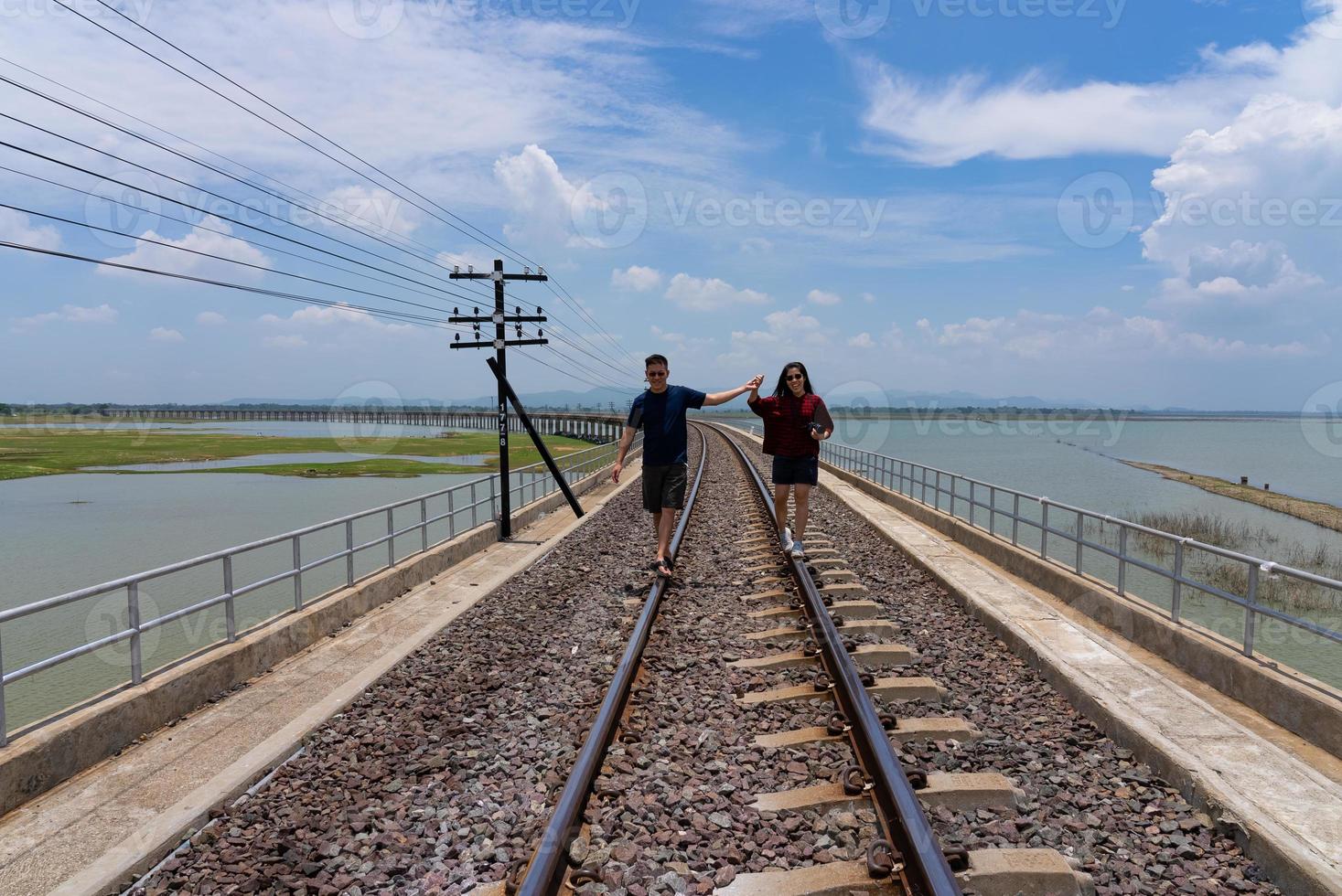 paar wandelen samen Aan spoorweg terwijl reizen Aan zomer vakantie foto