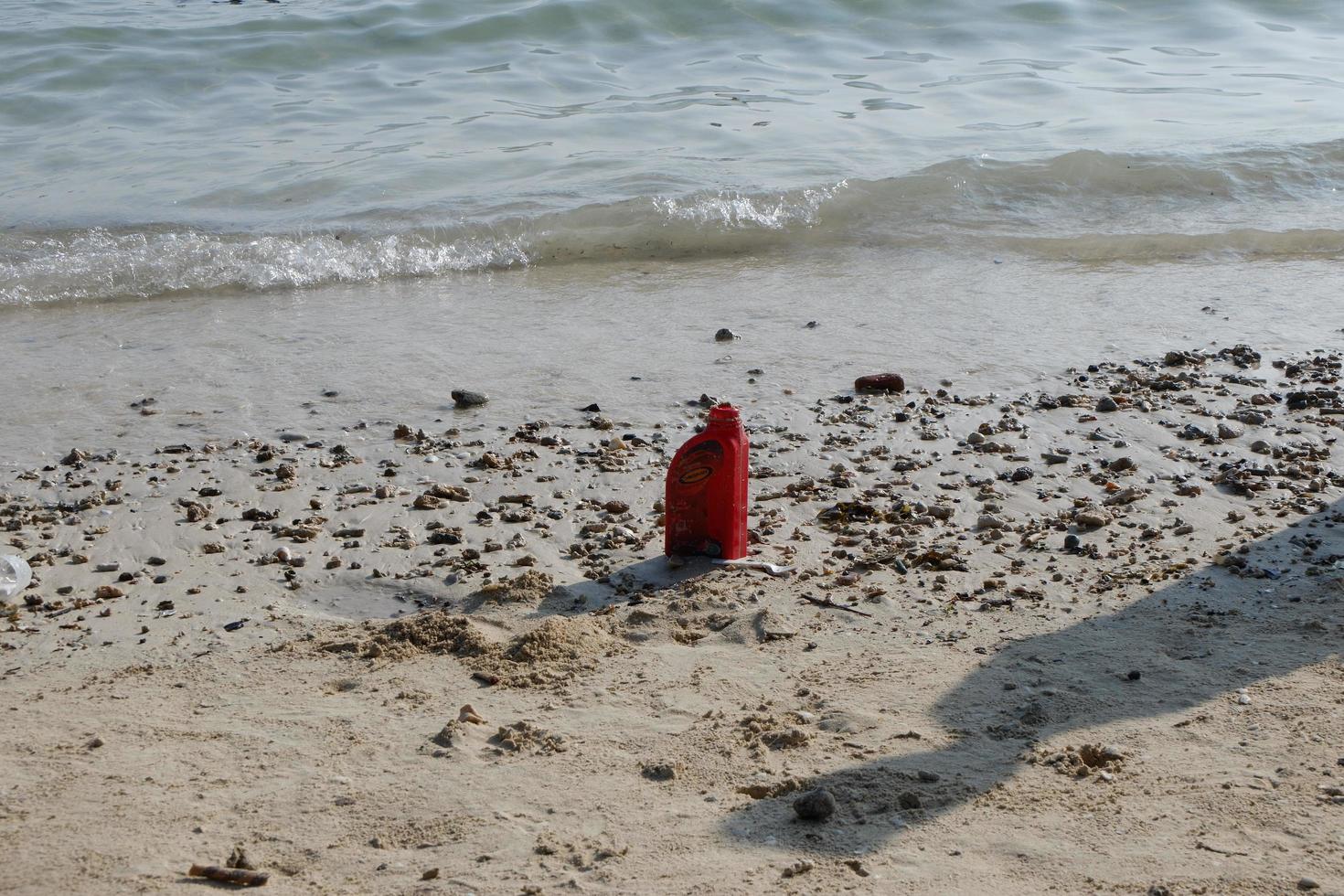 uitschot van rood olie fles is Aan de strand foto