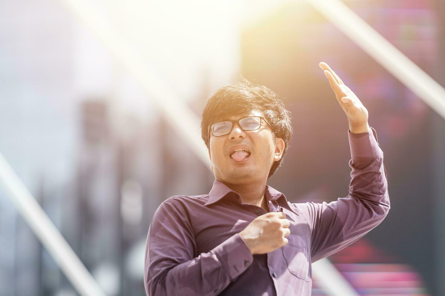 Aziatisch bedrijf Mens Purper met t-shirt onder zon schuilplaats door hand- Aan vervagen modern stad achtergrond. foto