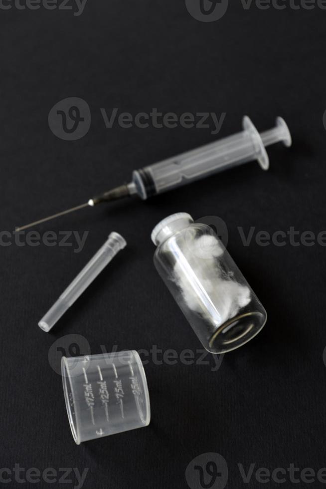 een leeg medisch injectiespuit en een glas fles Aan een zwart achtergrond. foto