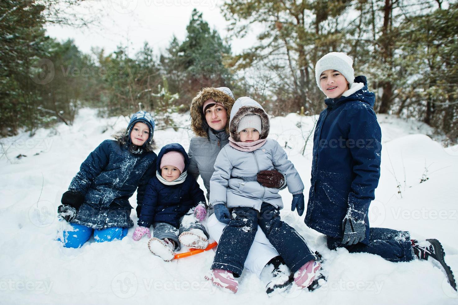 moeder met vier kinderen in de winternatuur. buiten in de sneeuw. foto