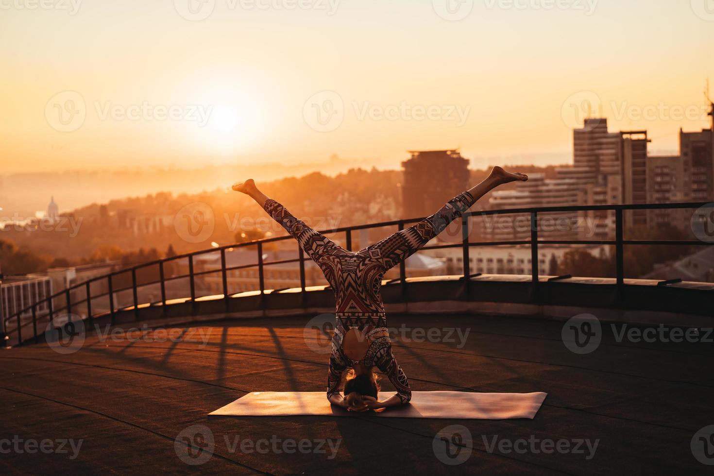 vrouw aan het doen yoga Aan de dak van een wolkenkrabber in groot stad. foto