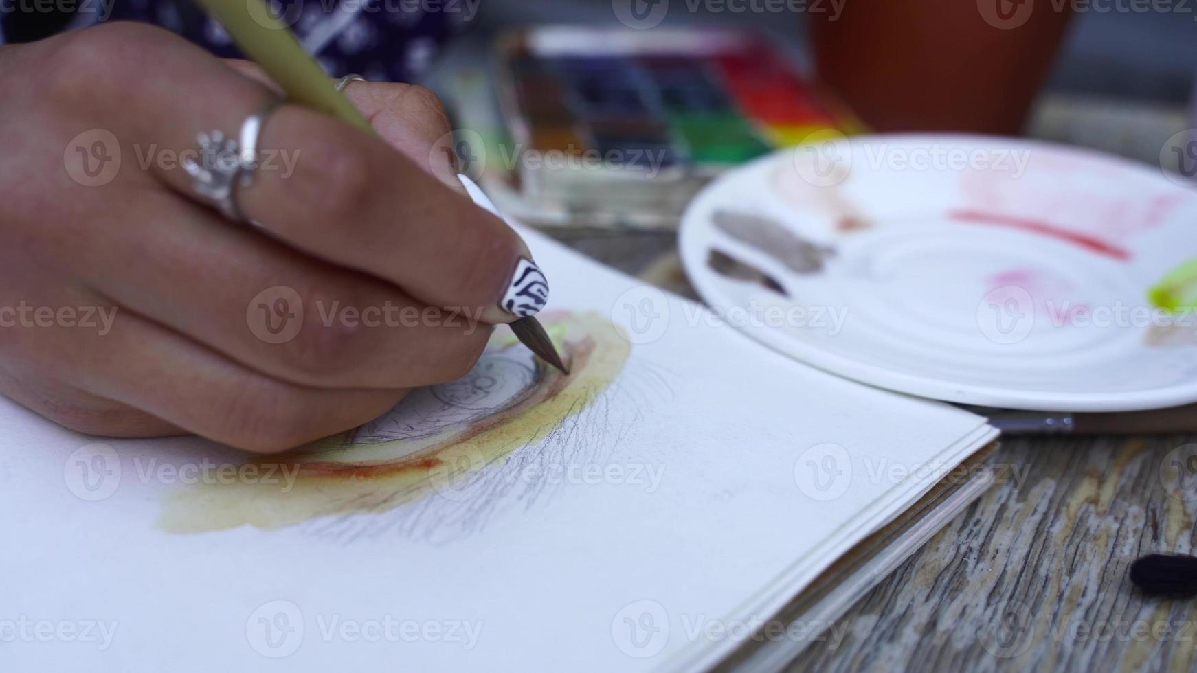 vrouw hand- trekt menselijk oog Aan schetsboek met een borstel foto