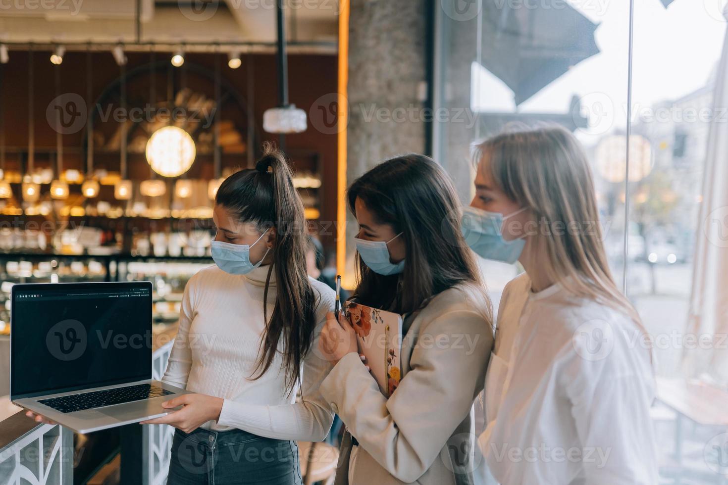 drie onderneemsters met hun gezicht maskers debatteren verschillend keer bekeken Aan werk foto