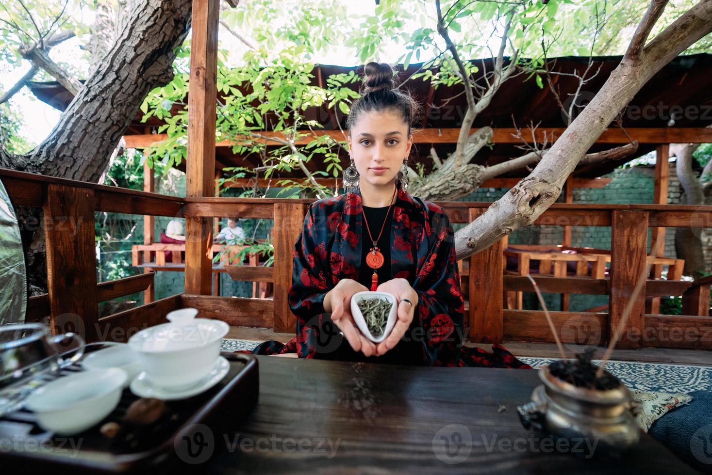 jong vrouw Holding een klein kom van groen kruiden thee foto