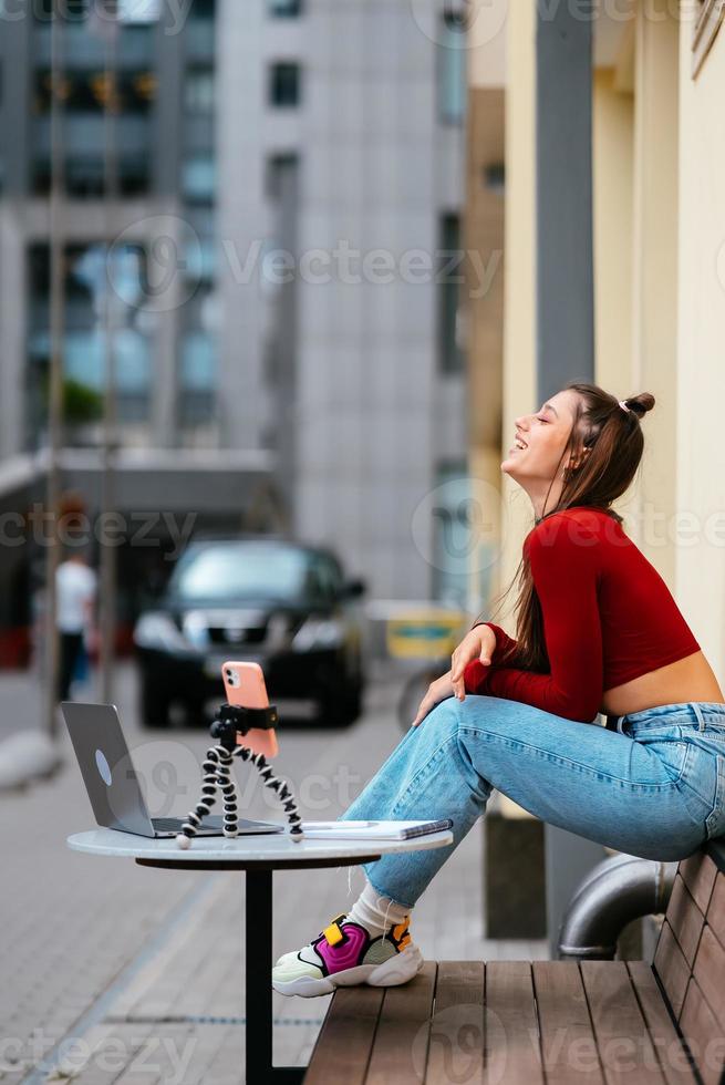 vrouw blogger in een zomer cafe streaming Aan de straat. foto
