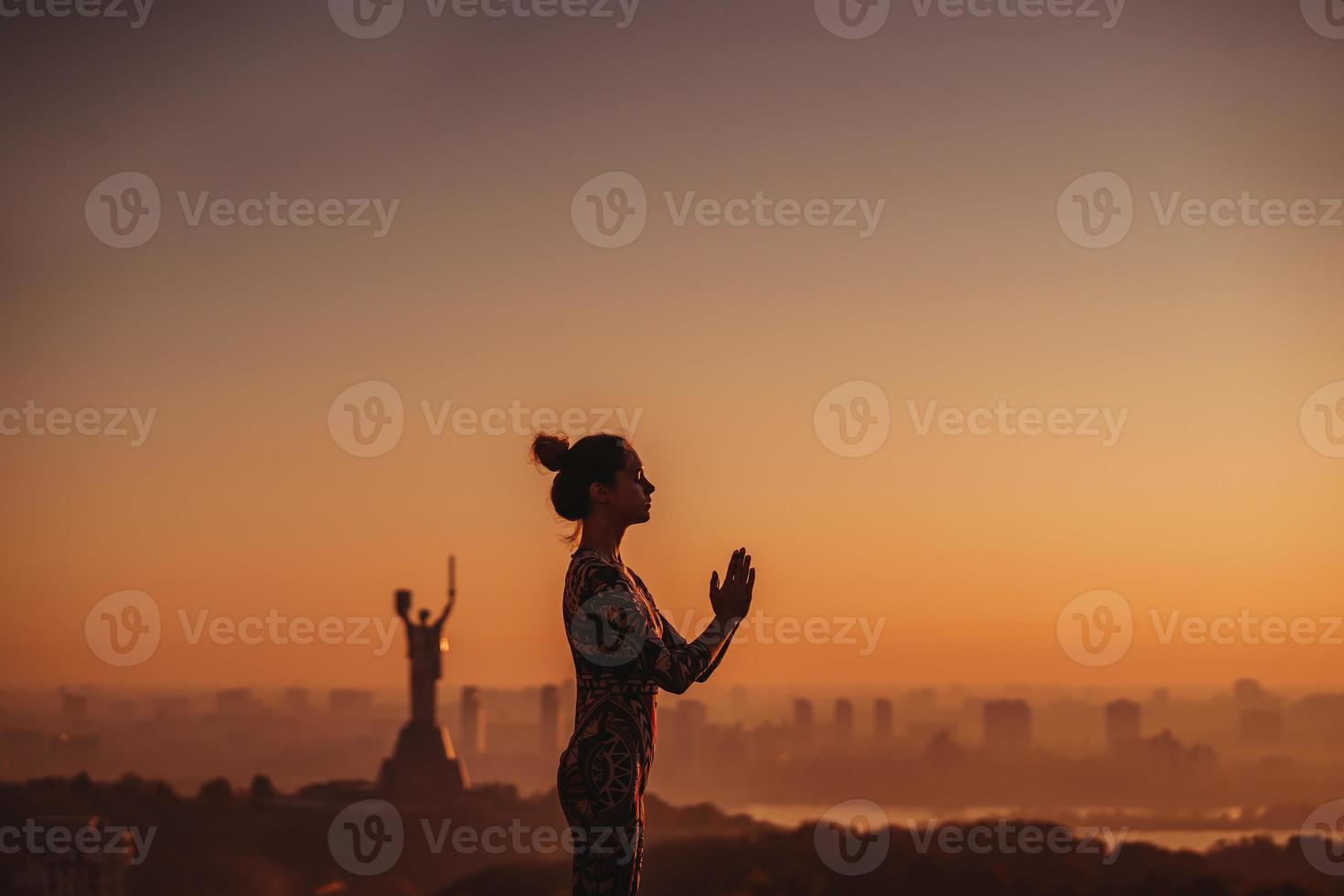 vrouw aan het doen yoga Aan de dak van een wolkenkrabber in groot stad. foto