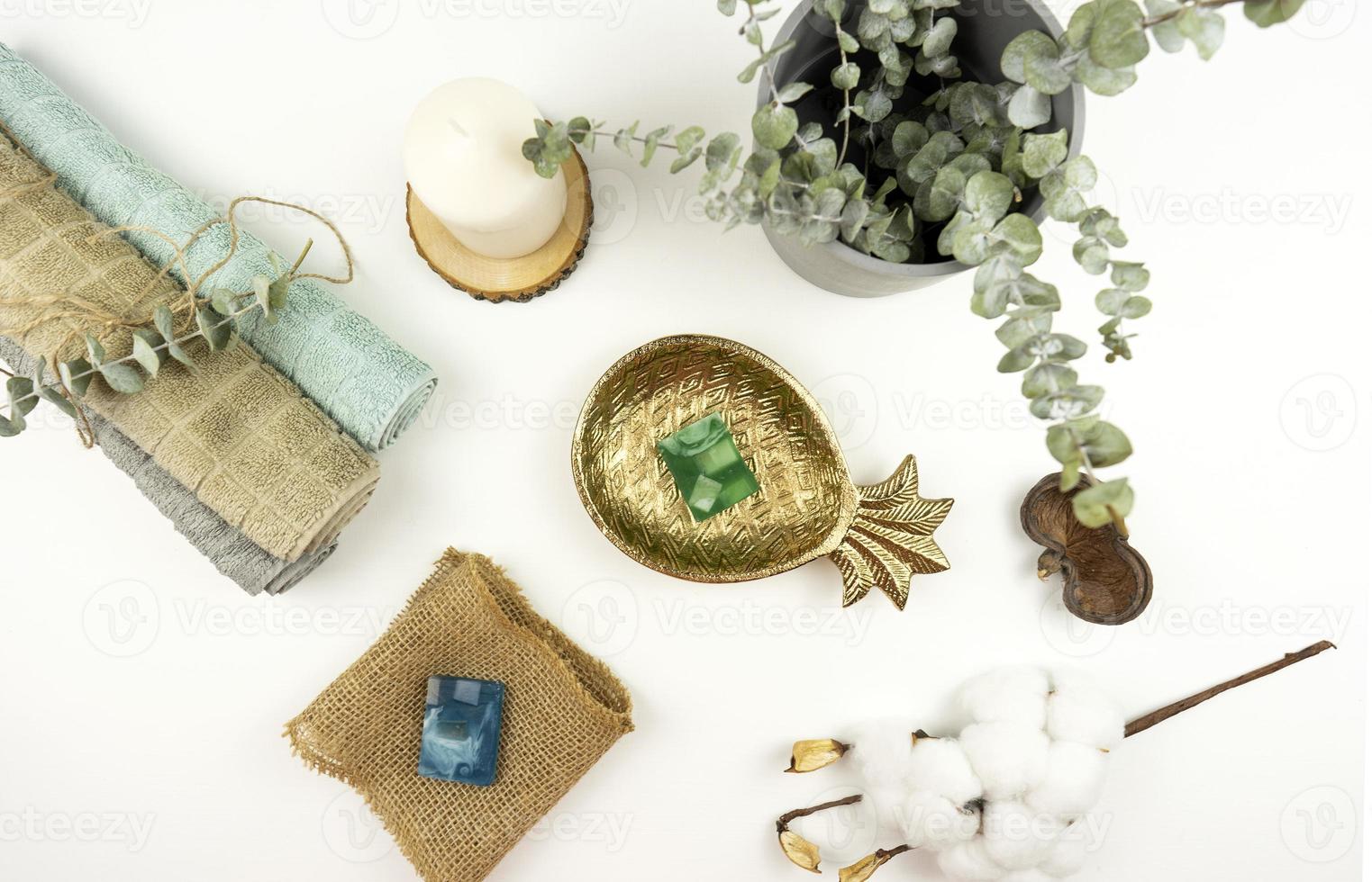 een vlak leggen van katoen handdoeken, hand- gemaakt zeep, een pot met eucalyptus en een Afdeling van katoen Aan een wit tafel in een modern badkamer foto