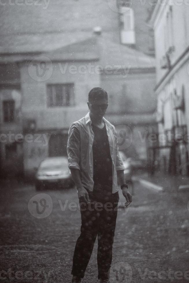 portret van zorgeloos knap jong Mens is gevoel vrij onder de regen foto
