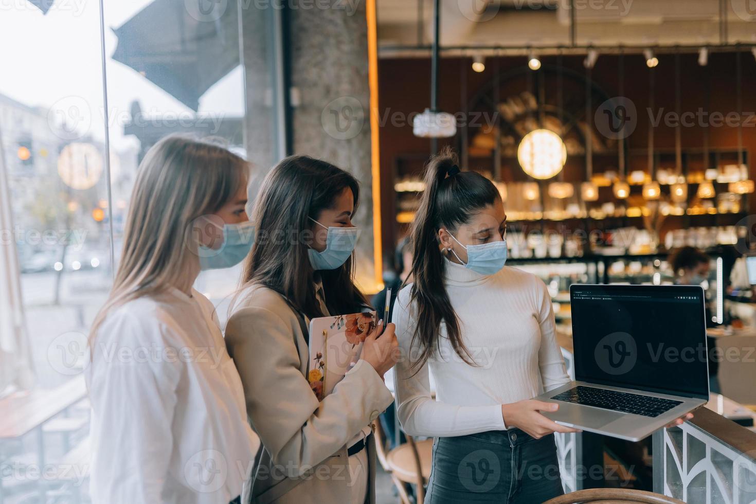 drie onderneemsters met hun gezicht maskers debatteren verschillend keer bekeken Aan werk foto