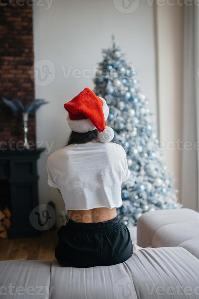 glimlachen vrouw met de kerstman hoed Aan hoofd in leven kamer foto