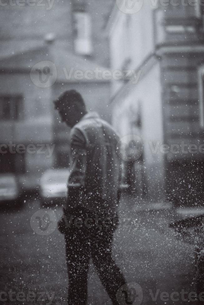 portret van zorgeloos knap jong Mens is gevoel vrij onder de regen foto