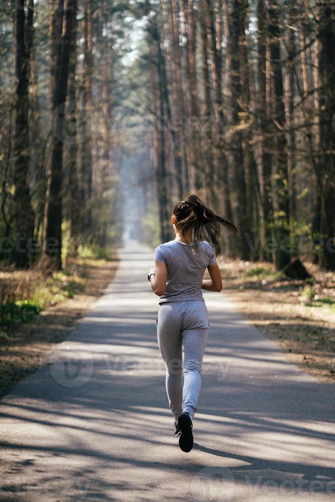 mooi jong vrouw rennen in groen park Aan zonnig zomer dag foto