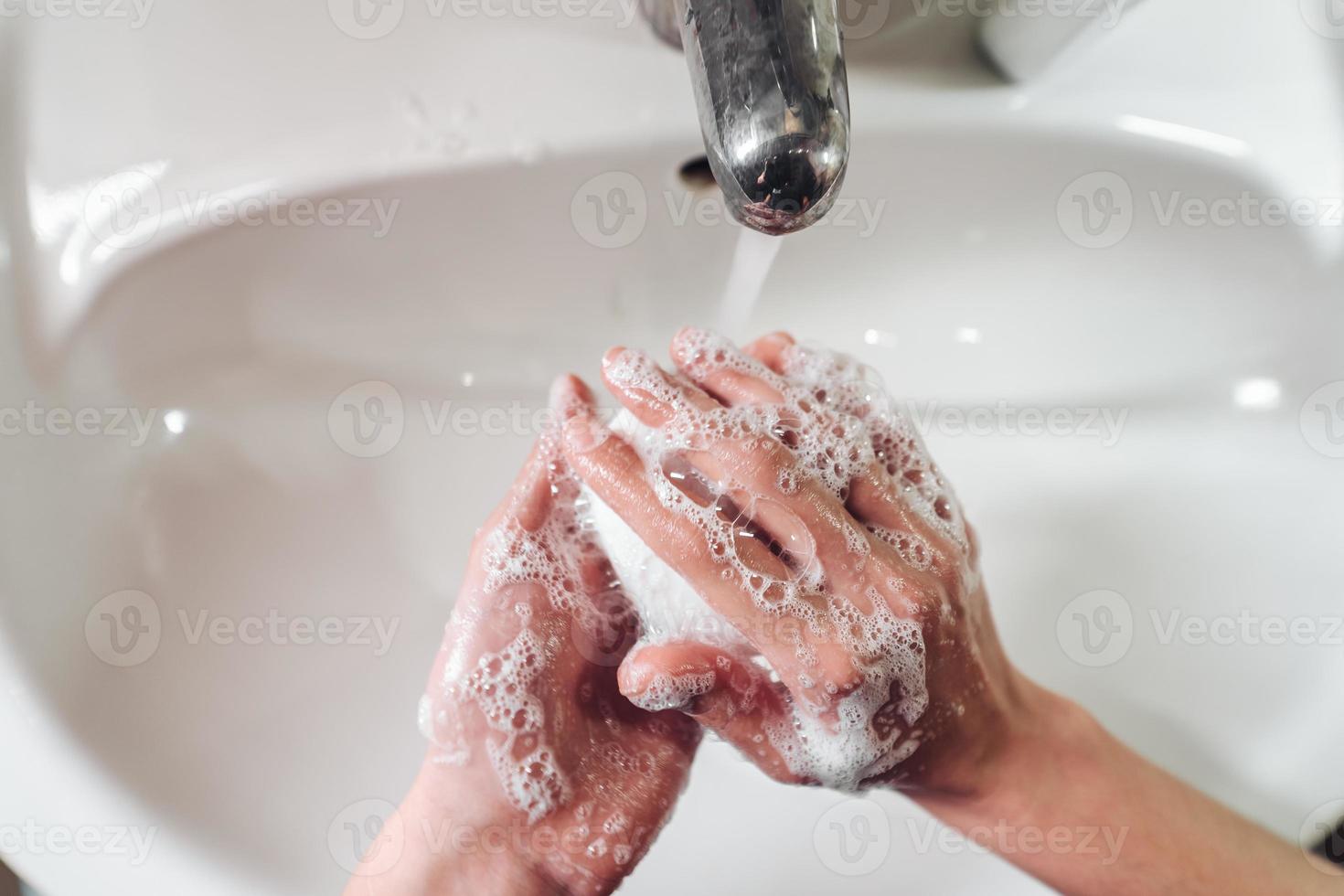 Mens het wassen handen naar beschermen tegen de coronavirus foto