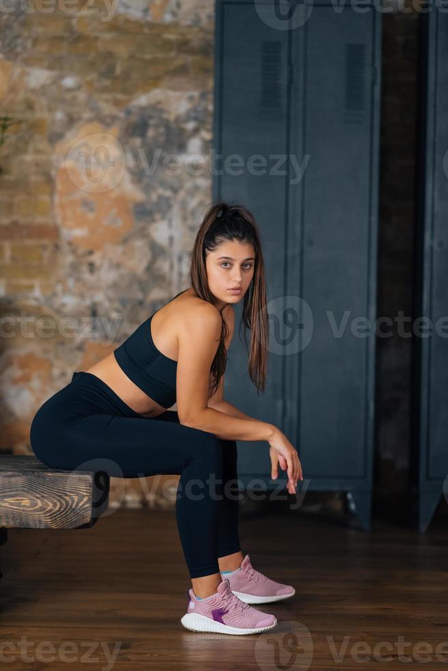 sportief vrouw in sportkleding resting Aan bank Bij geschiktheid. foto