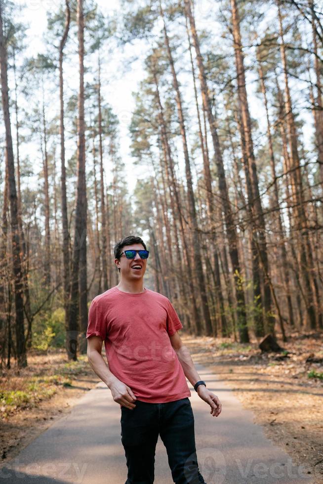 knap jong Mens in wit t-shirt en jeans buitenshuis in park, wandelen in de park foto