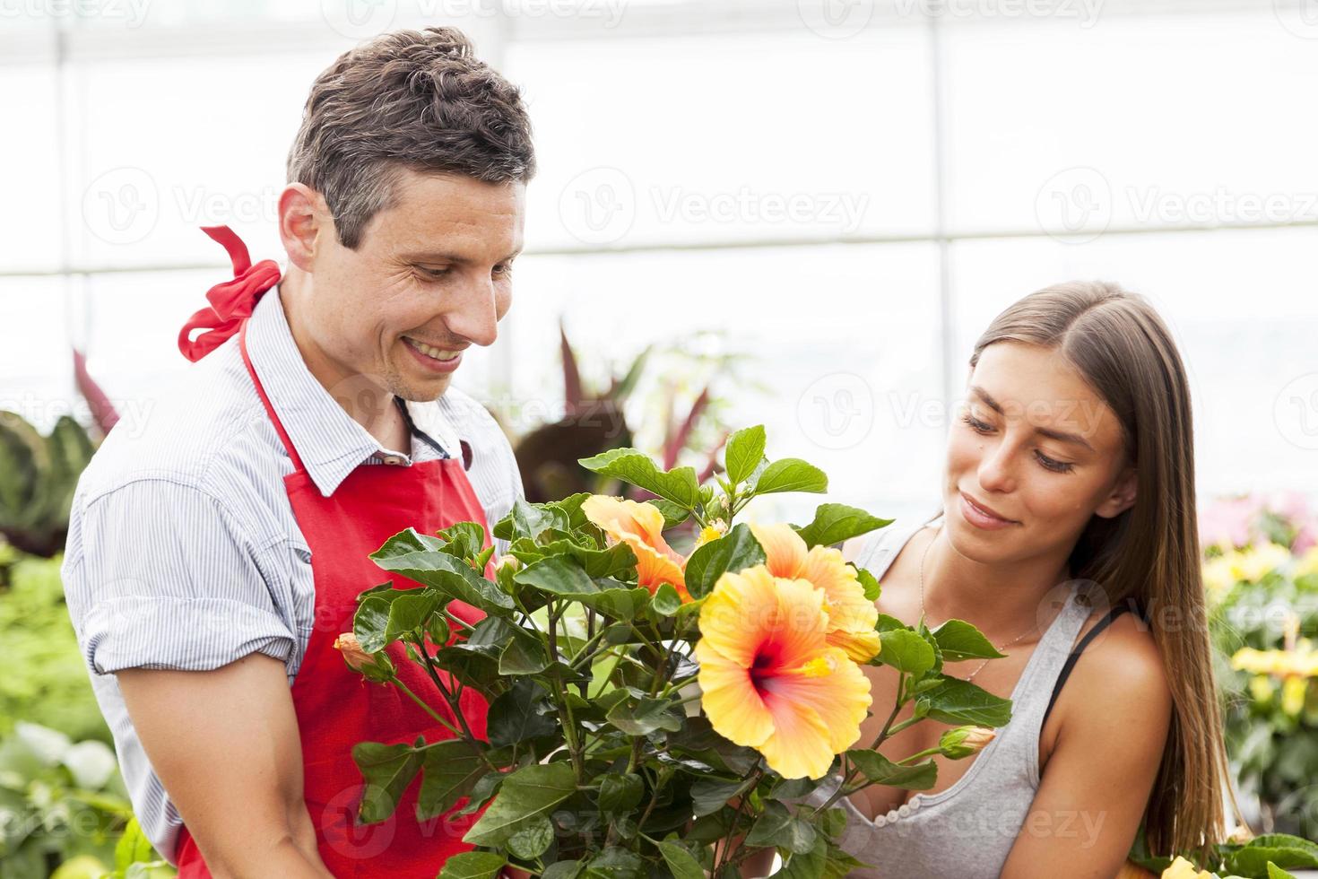 lachende verkoper verkoopt een plant aan een mooie klant foto