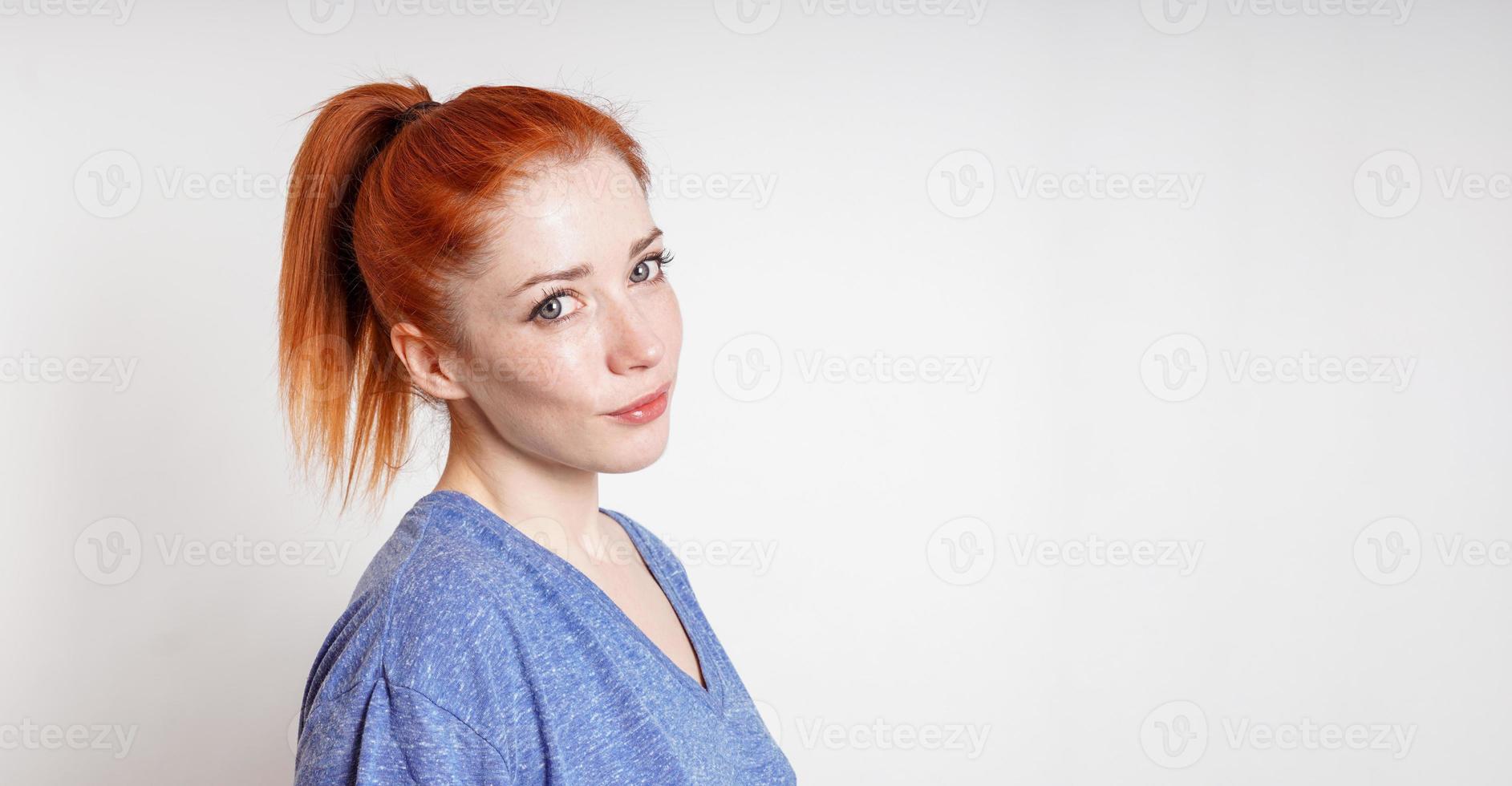 jong vrouw met rood haar- gebonden in paardenstaart kantelt haar hoofd glimlachen foto