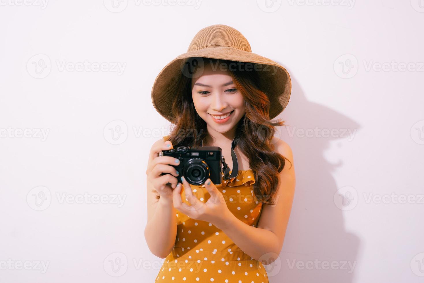 dichtbij omhoog portret van een glimlachen mooi meisje in jurk nemen foto Aan een retro camera geïsoleerd over- roze achtergrond