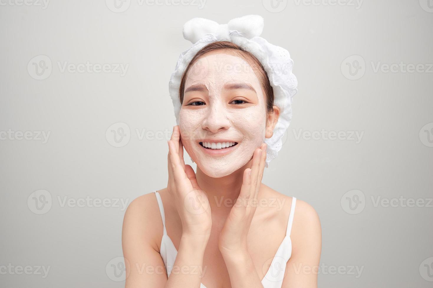vrolijk jong Aziatisch vrouw met gelaats klei masker geïsoleerd Aan wit achtergrond. foto