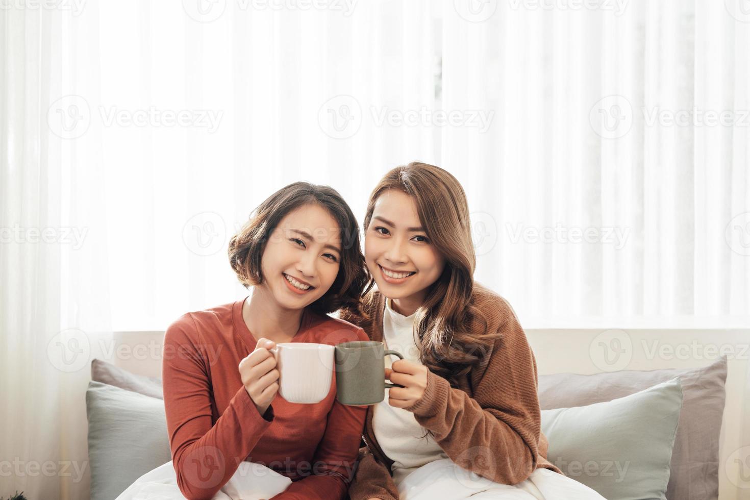 gelukkig vrienden pratend en drinken koffie en thee zittend Aan een bankstel Bij huis foto
