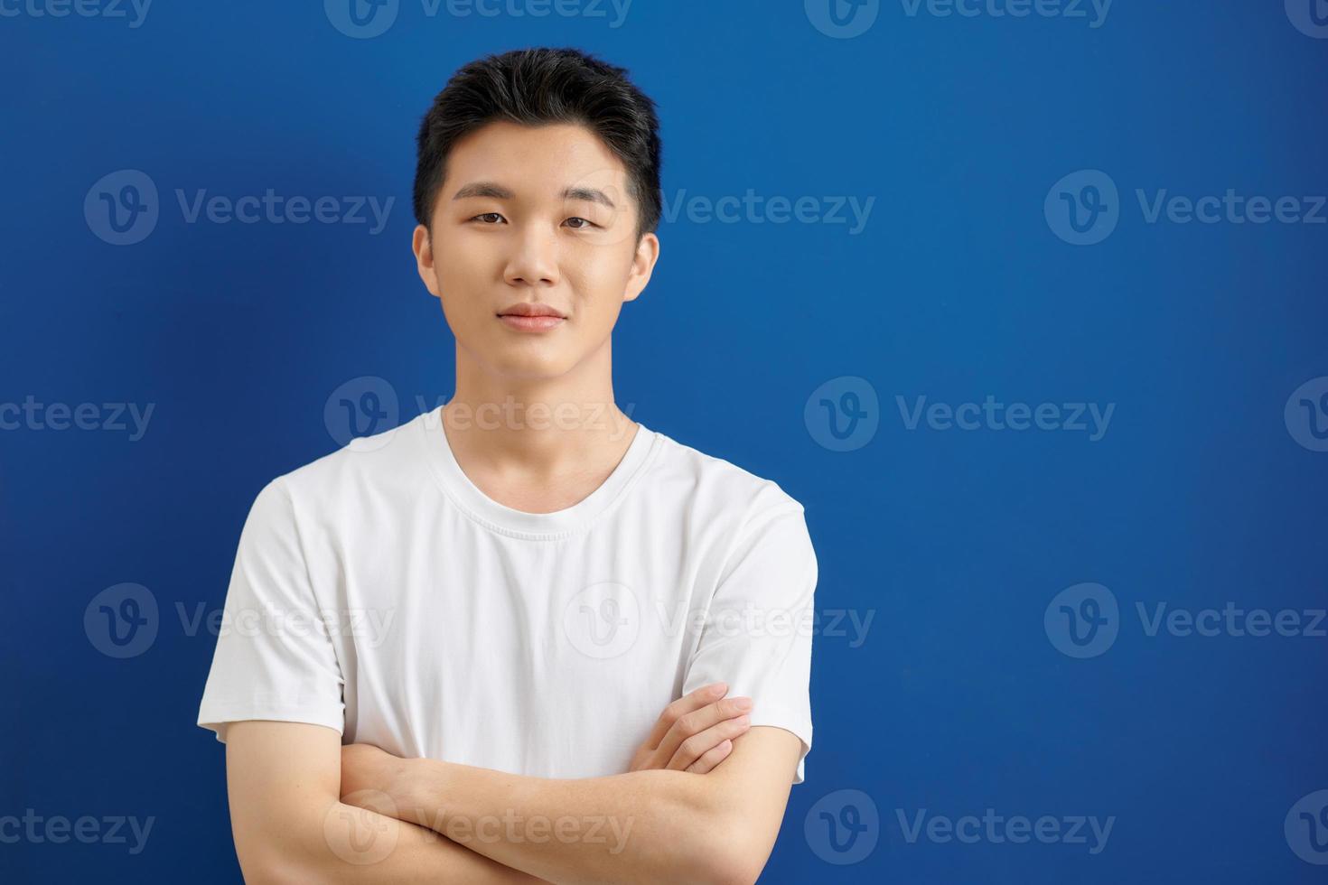 glimlachen knap Mens in t-shirt staand met gekruiste armen geïsoleerd Aan blauw achtergrond foto