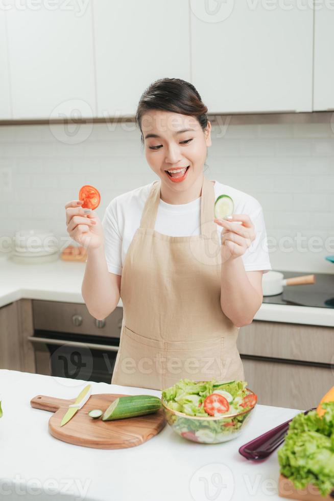 gezond vrouw maakt vers groente salade met olijf- olie, tomaat en salade foto