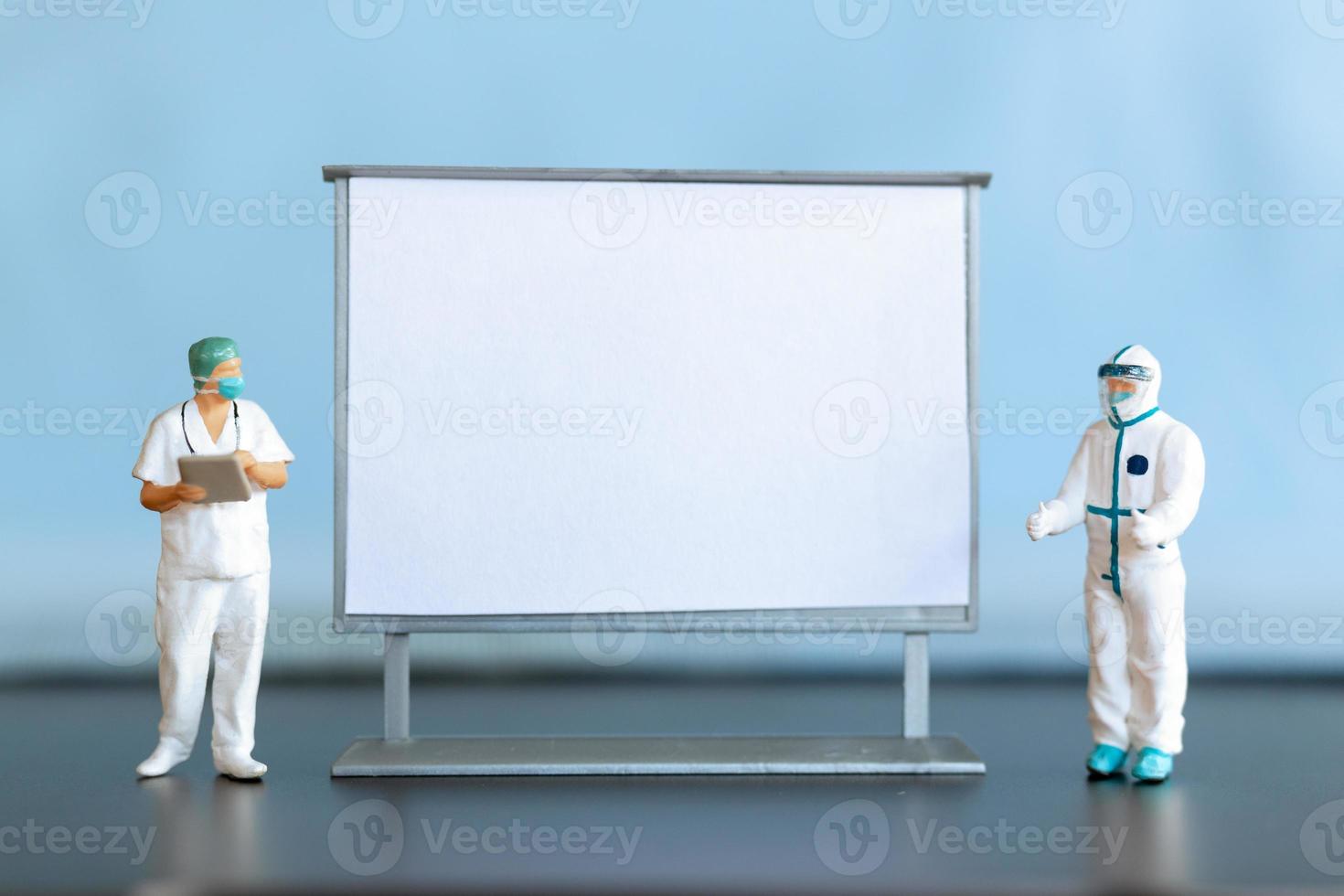 miniatuur dokter staand met blanco wit bord foto