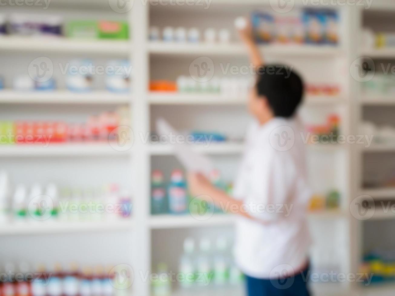 vervagen apotheker die medicijnen van de plank in de apotheek neemt foto