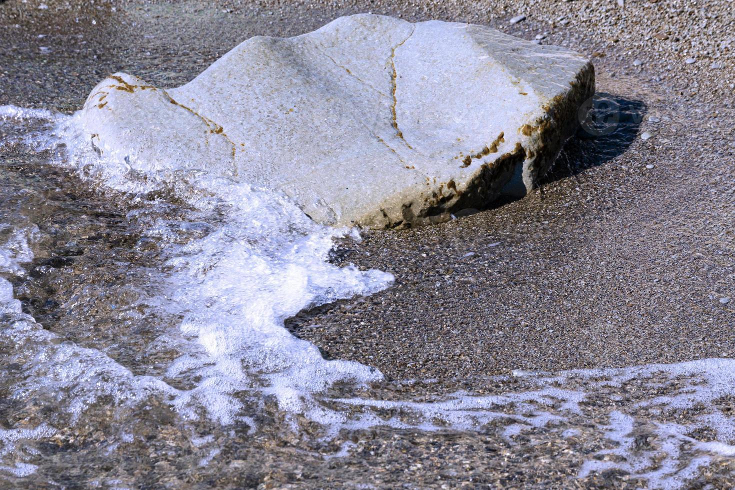 kust- Golf broodjes Aan klein steentjes Aan de strand tegen de achtergrond van een kei. achtergrond foto