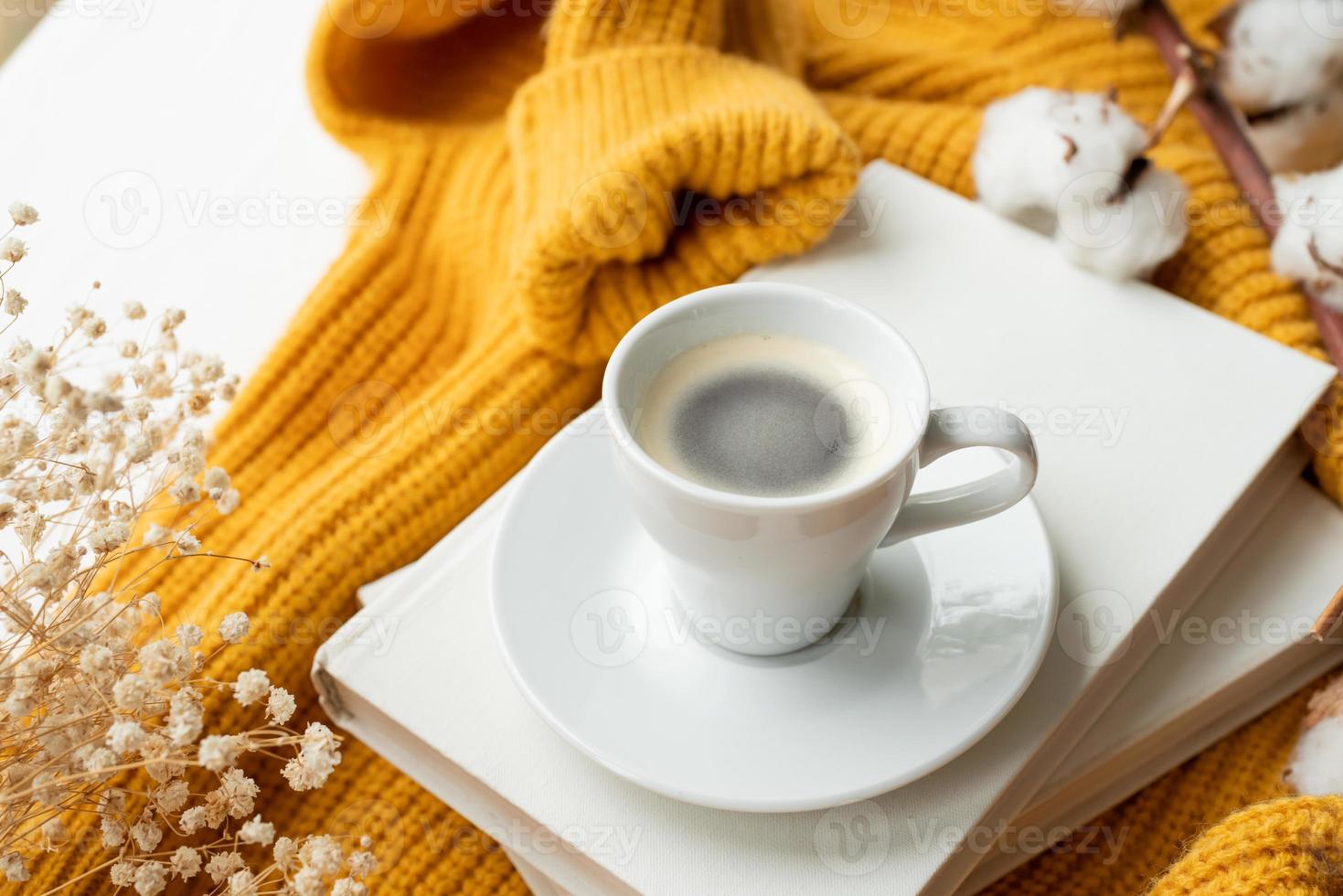 knus samenstelling van warm geel trui, wit boeken , kop van heet koffie en droog bloemen , top visie foto