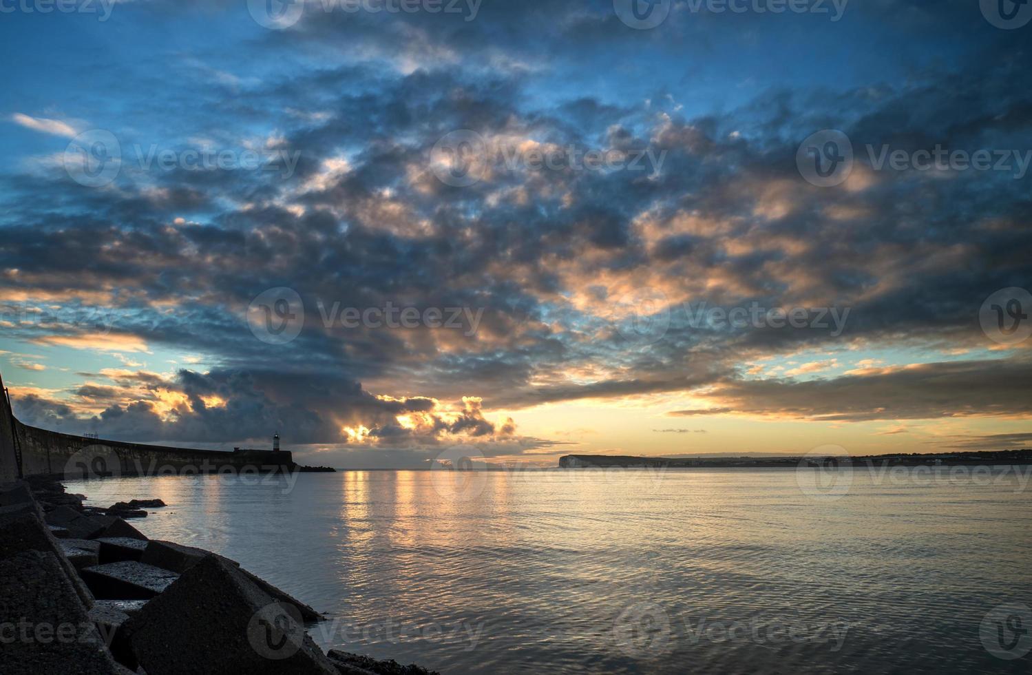 mooie levendige zonsopgang hemel over kalme oceaan met vuurtoren foto