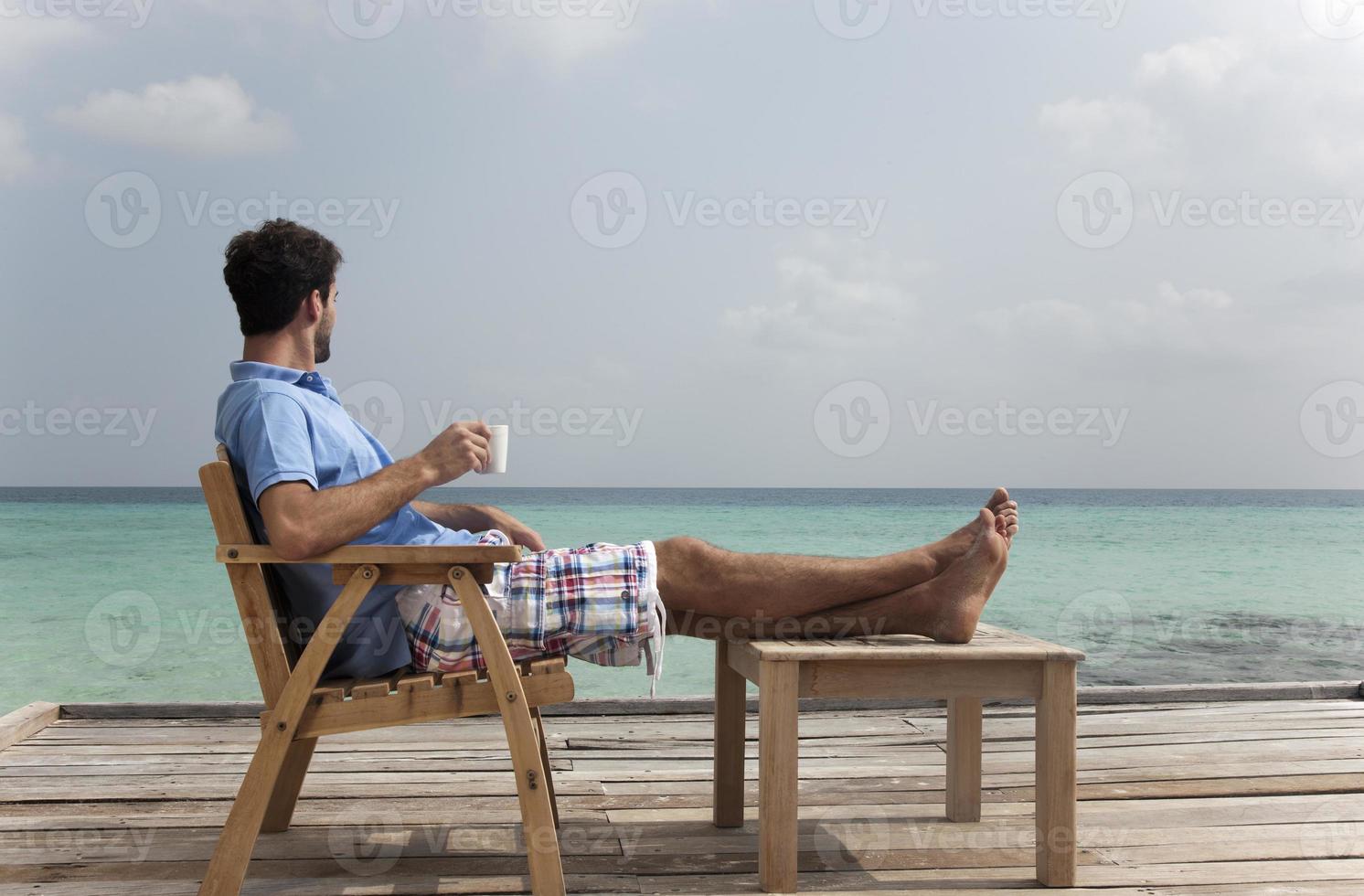 man koffie drinken op het dek op het strand foto