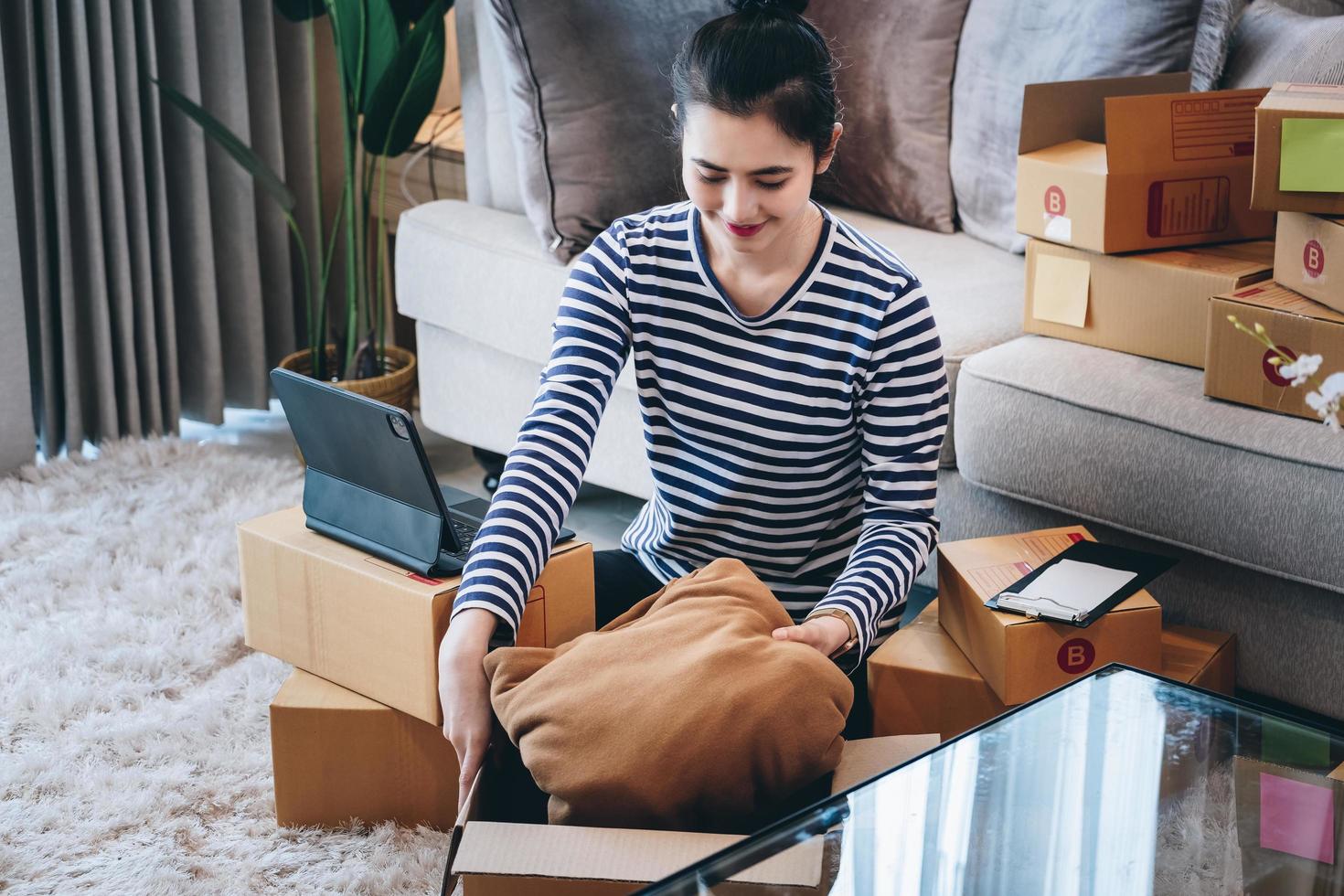 online merchandising bedrijf idee, een mooi meisje is inpakken kussens in een Verzending doos naar bereiden naar sturen items naar klanten volgens naar bestellingen ontvangen van klanten foto